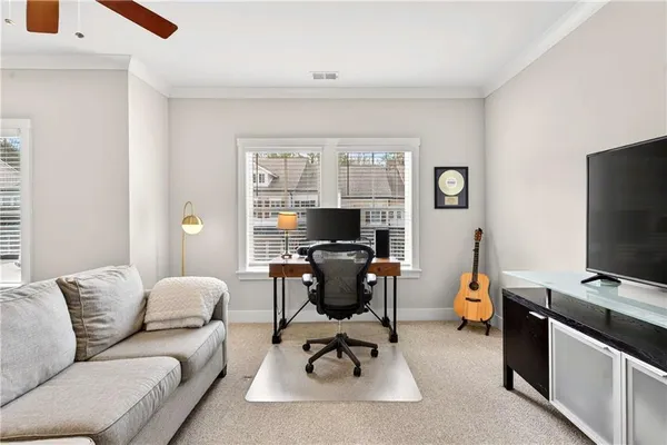 a work room with furniture a flat screen tv and a window
