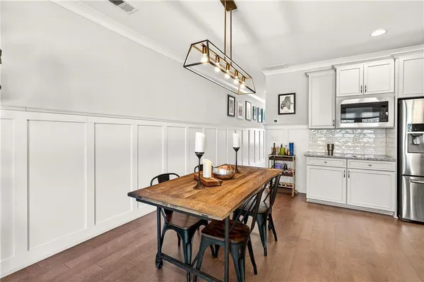 a kitchen with stainless steel appliances granite countertop a stove a refrigerator a kitchen island a table and chairs in it