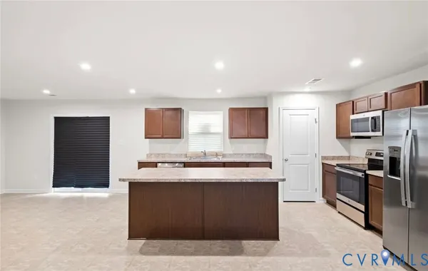 a kitchen with stainless steel appliances granite countertop a stove top oven a sink and a refrigerator
