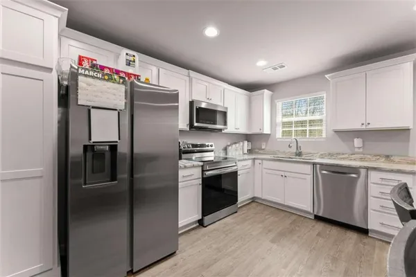a kitchen with granite countertop stainless steel appliances cabinets a sink and a window