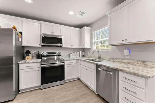 a kitchen with stainless steel appliances granite countertop a sink stove a refrigerator and cabinets