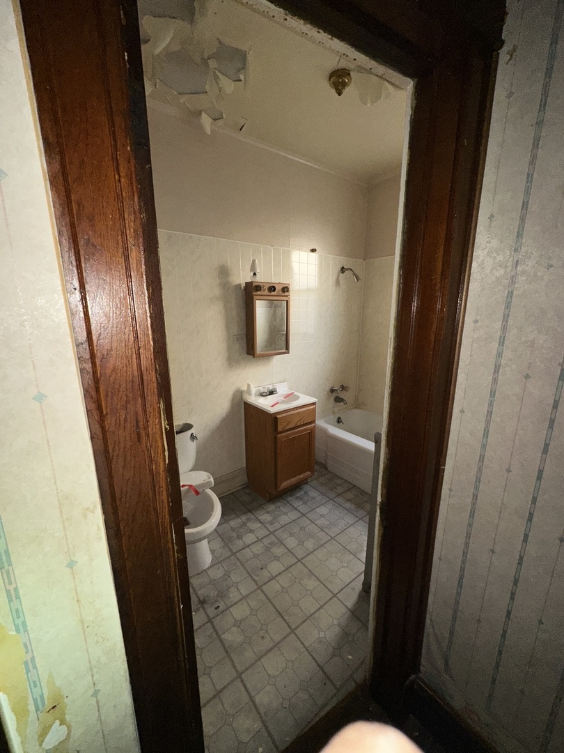 7425 South Harvard Avenue Chicago, IL 60621 - Photo 27 of 31 a bathroom with a sink a toilet a mirror and vanity
