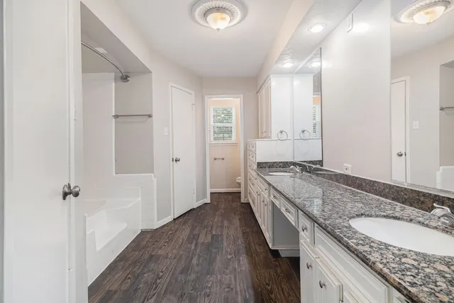 a bathroom with a granite countertop double vanity sink a mirror and a shower