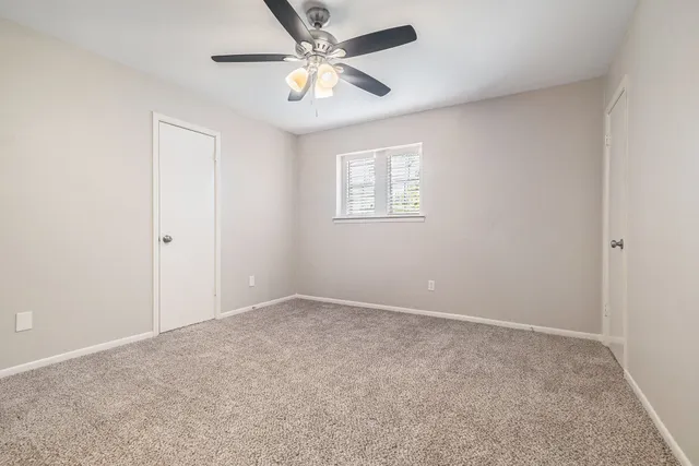 an empty room with a window and a fan