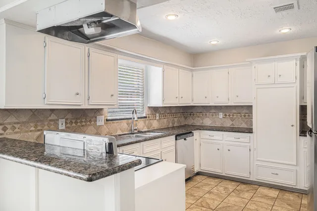 a kitchen with granite countertop a sink a stove and cabinets