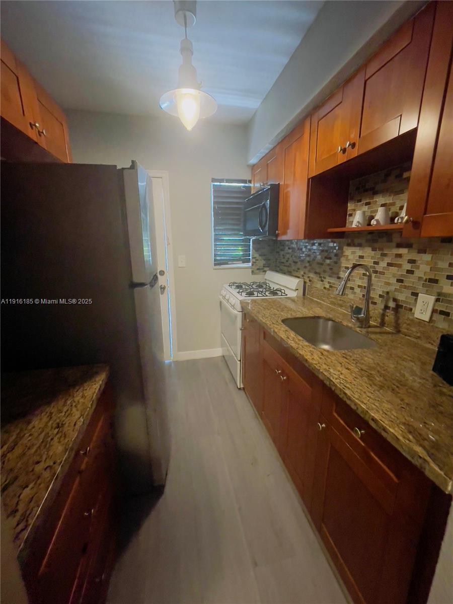 7710 Harding Avenue, Unit 403 Miami Beach, FL 33141 - Photo 5 of 7 a large kitchen with a sink and a refrigerator