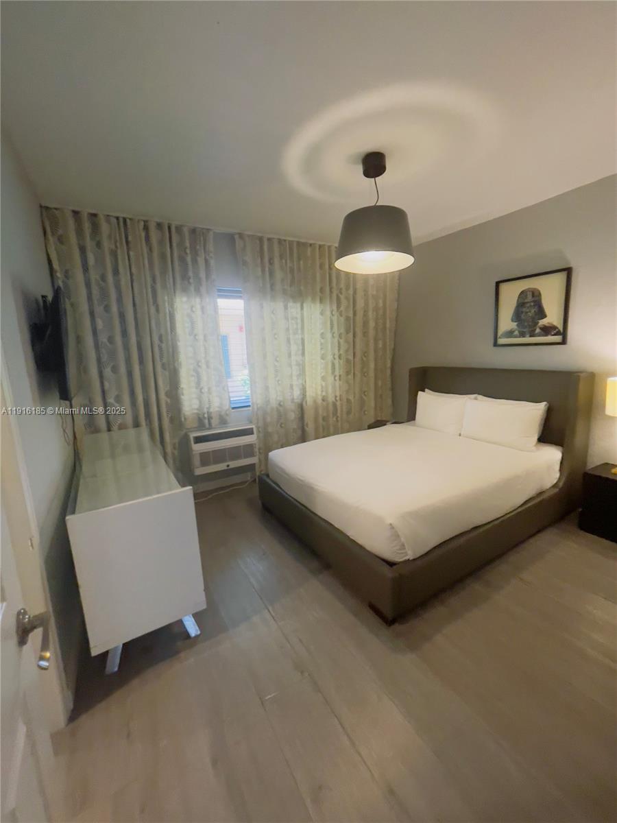 7710 Harding Avenue, Unit 403 Miami Beach, FL 33141 - Photo 6 of 7 a bedroom with a bed and a chandelier