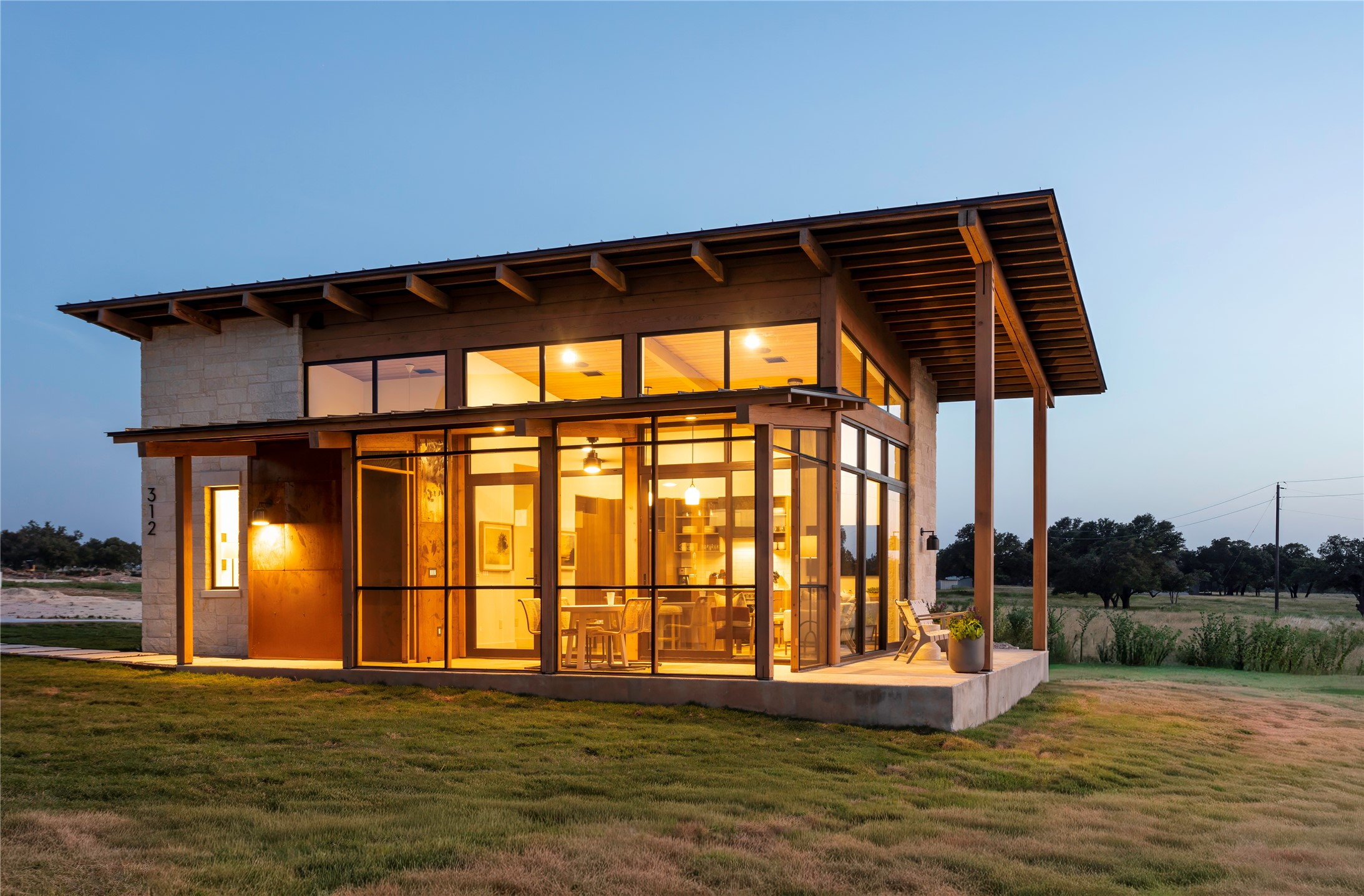 312 Hye Springs Road, Unit 106 Hye, TX 78635 - Photo 14 of 17 Contemporary exterior elevation featuring expansive windows, screened patio space, and clean modern ranch architecture.