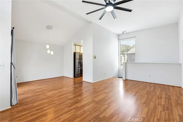 a view of an empty room with wooden floor and a ceiling fan