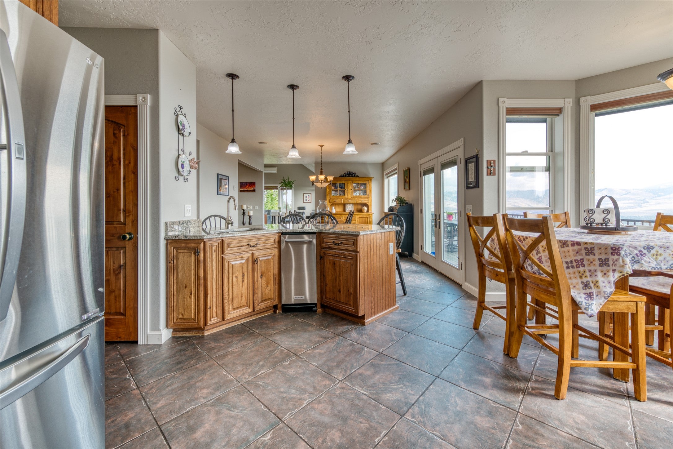 16374 Folsom Road Florence, MT 59833 - Photo 31 of 98 Kitchen featuring freestanding refrigerator, brown cabinets, pendant lighting, a peninsula, and light stone countertops