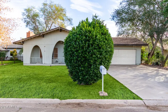 a view of a house with a yard plants and large tree