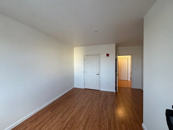 a view of an empty room with wooden floor and closet