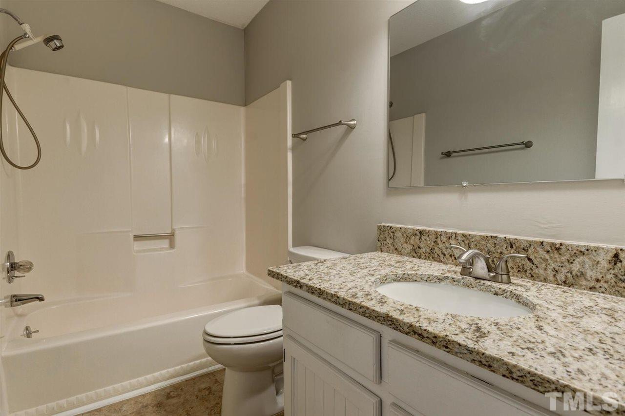 6329 Rushingbrook Drive Raleigh, NC 27612 - Photo 22 of 30 a bathroom with a granite countertop sink a toilet and shower