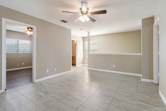 a view of a livingroom with a chandelier fan and windows
