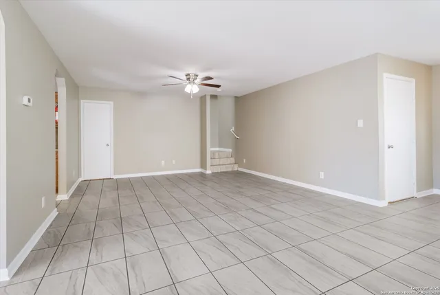 an empty room with windows and chandelier fan