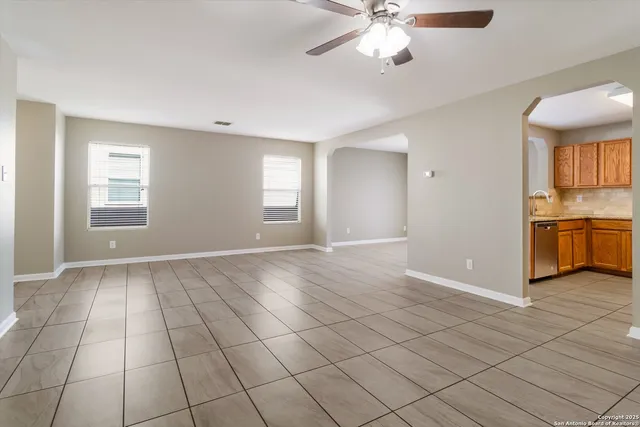 a view of an empty room with window and chandelier fan