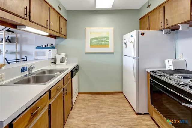 a kitchen with stainless steel appliances a refrigerator a sink and wooden cabinets