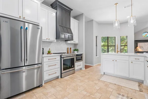 a kitchen with white cabinets stainless steel appliances and window