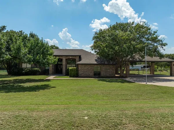 a front view of a house with a yard and a large tree