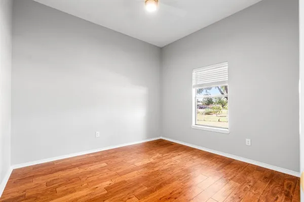 a view of an empty room with wooden floor and a window