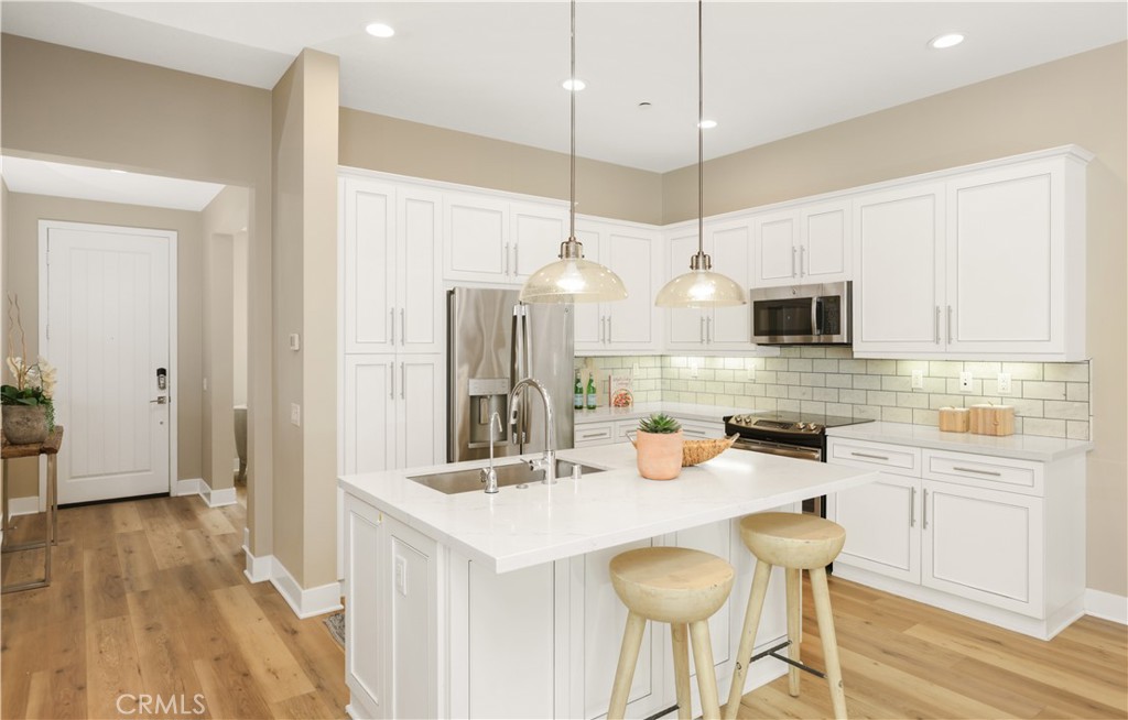 245 Follyhatch Irvine, CA 92618 - Photo 12 of 44 a kitchen with granite countertop a sink a stove a refrigerator and white cabinets with wooden floor