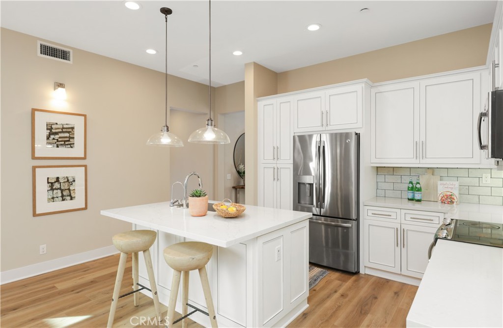 245 Follyhatch Irvine, CA 92618 - Photo 13 of 44 a kitchen with stainless steel appliances a refrigerator a sink dishwasher a stove and white cabinets with wooden floor