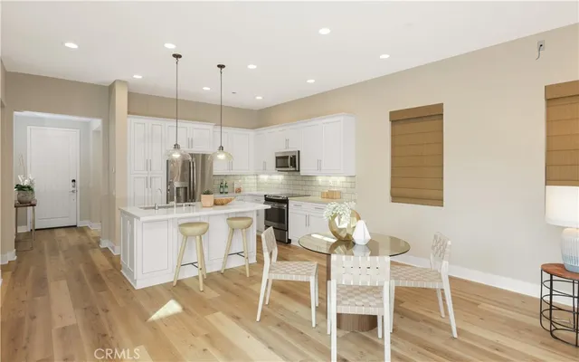 a kitchen with stainless steel appliances kitchen island granite countertop a dining table chairs and white cabinets