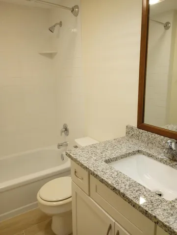 a bathroom with a granite countertop sink toilet and shower