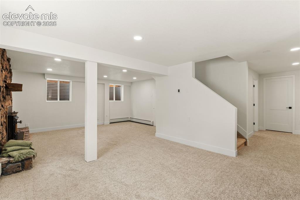11665 Greentree Road Colorado Springs, CO 80908 - Photo 30 of 43 Finished below grade area with recessed lighting, light colored carpet, stairway, a fireplace with raised hearth, and baseboard heating