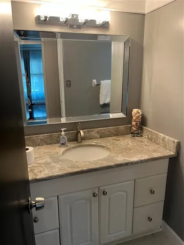 a bathroom with a granite countertop sink and a mirror