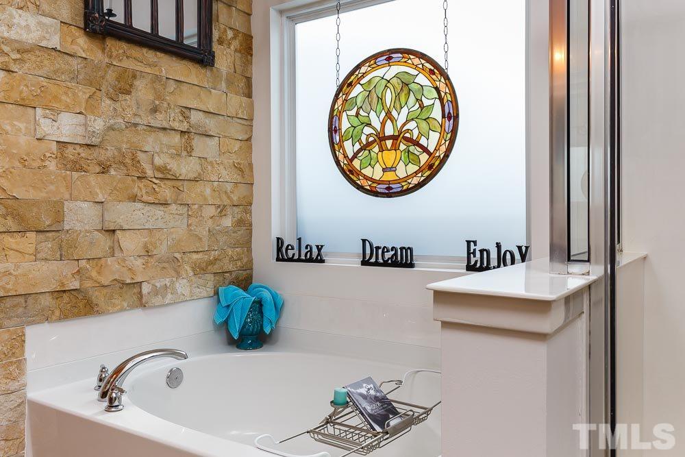 131 Daneborg Road Durham, NC 27703 - Photo 13 of 25 Spa-like retreat with a custom stone wall and privacy window for natural light . . . treat yourself to a luxury bath every day!