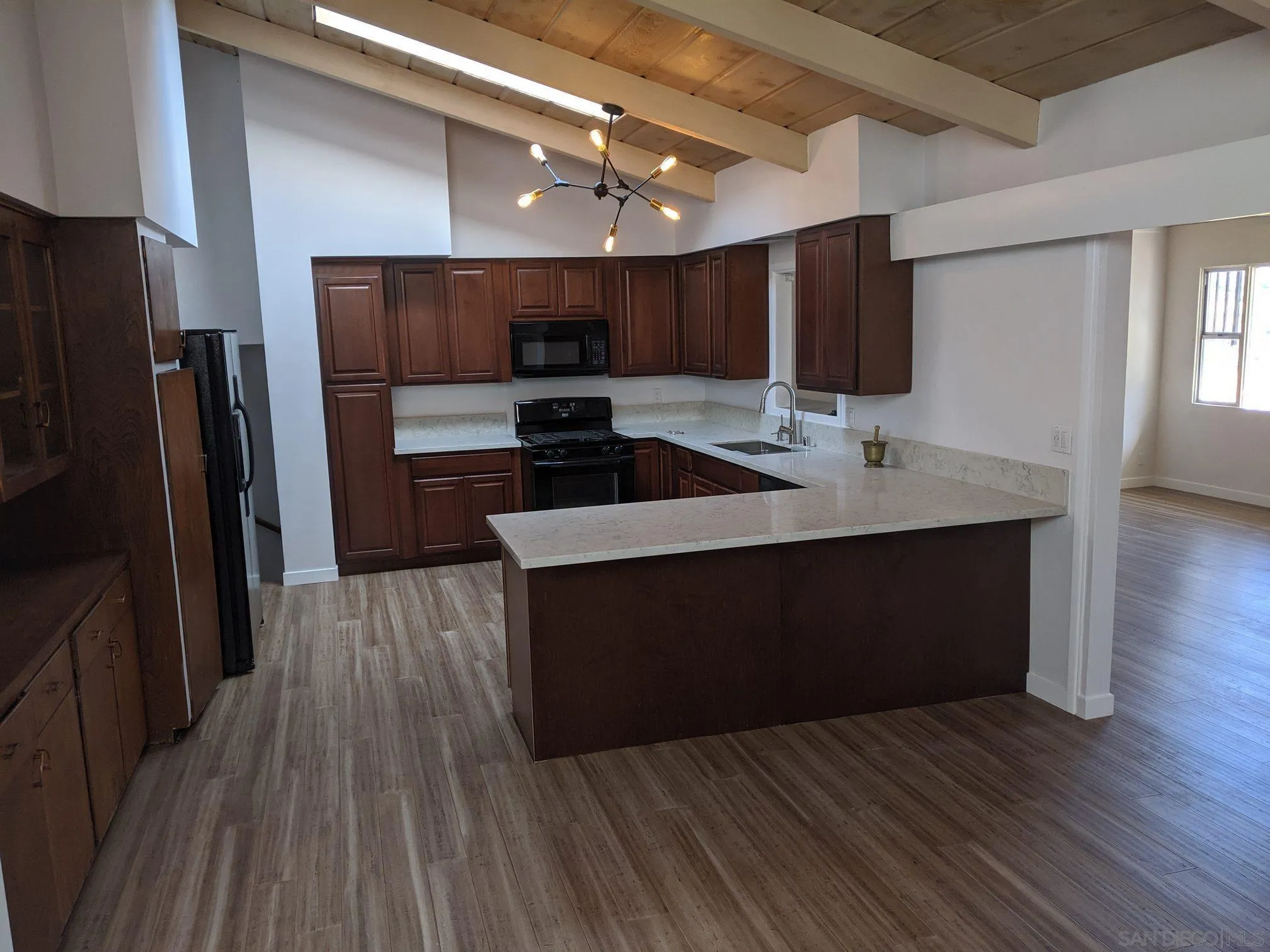 5451 Redding Road San Diego, CA 92115 - Photo 15 of 37 a kitchen with stainless steel appliances kitchen island granite countertop a refrigerator a sink and wooden floor