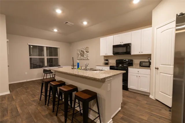 a kitchen with kitchen island granite countertop a sink and a stove top oven with wooden floor