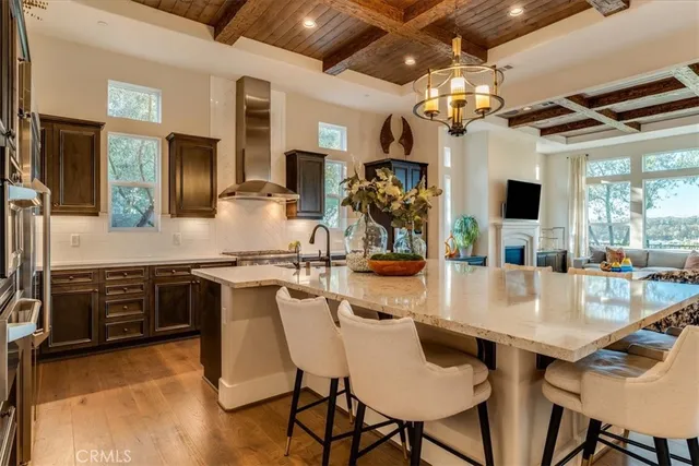 a kitchen with stainless steel appliances granite countertop a stove top oven a sink dishwasher a dining table and chairs with wooden floor