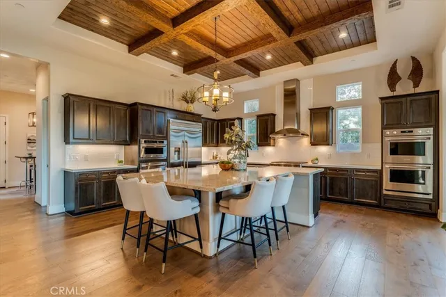 a kitchen with stainless steel appliances kitchen island granite countertop a table chairs sink and cabinets