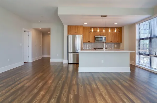 a living room with stainless steel appliances kitchen island wooden floors and kitchen view