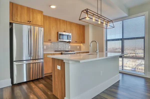 a kitchen with stainless steel appliances granite countertop a refrigerator a stove and a sink with wooden floor