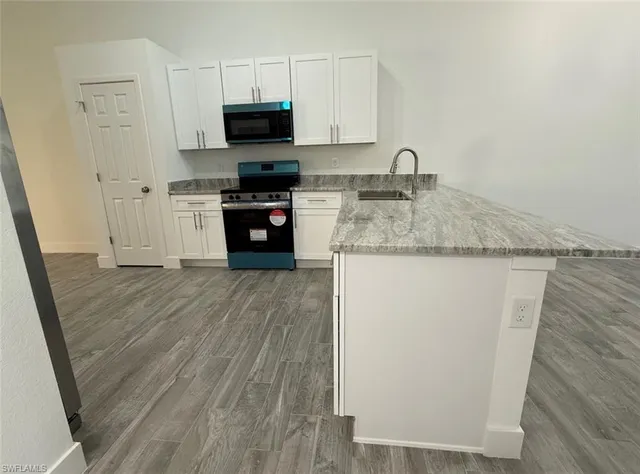 a kitchen with stainless steel appliances granite countertop a sink stove and microwave