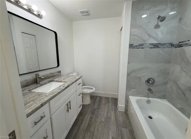 a bathroom with a granite countertop sink a toilet and bathtub