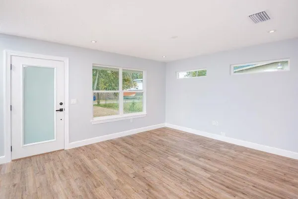 an empty room with wooden floor and windows
