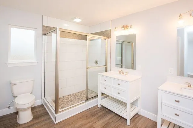 a view of a hallway with wooden floor and a bathroom