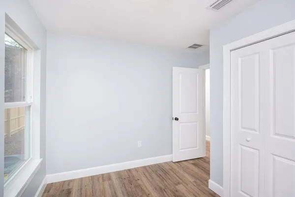 a view of an empty room with wooden floor and a bathroom