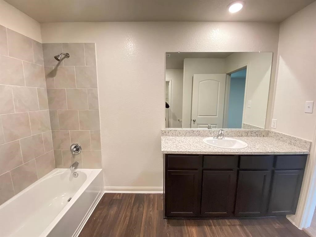 213 Allington Circle Jarrell, TX 76537 - Photo 7 of 16 a bathroom with a granite countertop sink a bathtub a mirror a vanity and bathtub