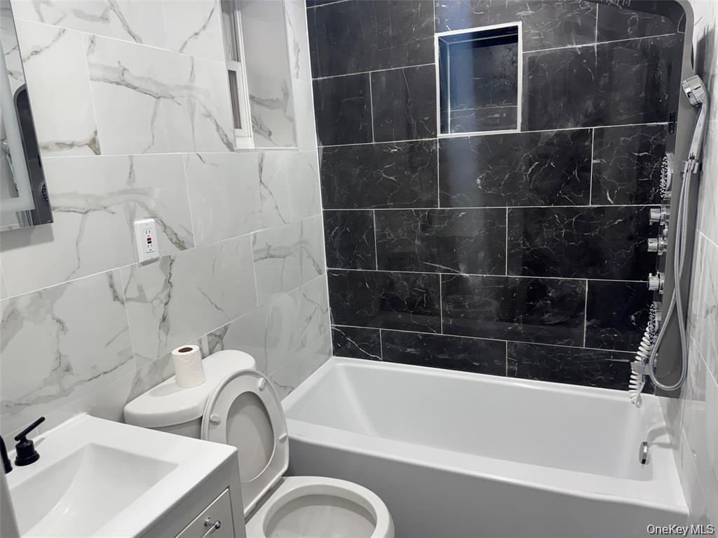 152 Evans Avenue Freeport, NY 11520 - Photo 2 of 12 Bathroom featuring vanity, tile walls, and shower / tub combination
