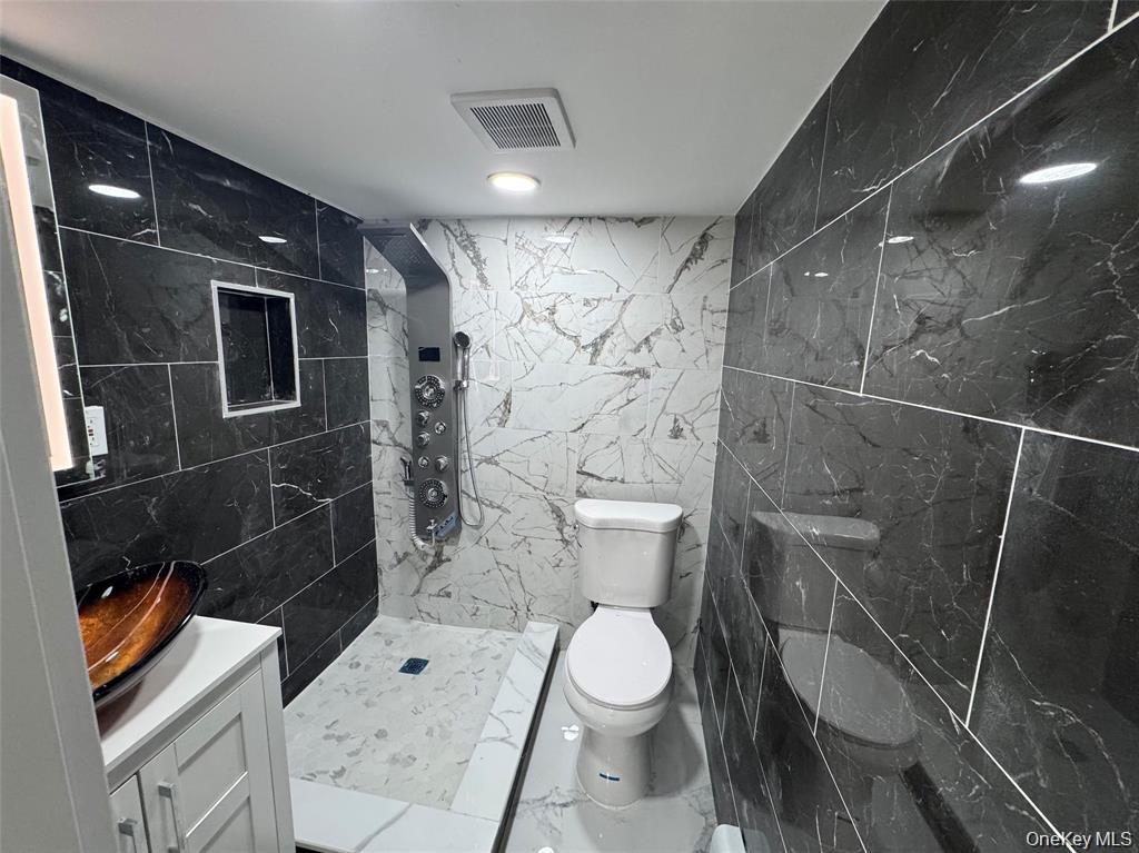 152 Evans Avenue Freeport, NY 11520 - Photo 9 of 12 Bathroom with tile walls, a marble finish shower, and vanity