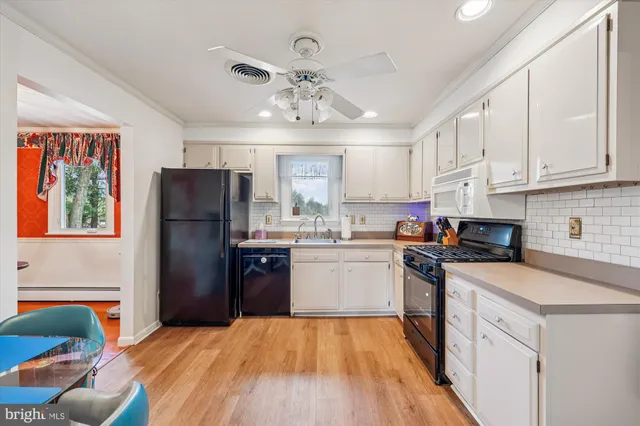 a kitchen with stainless steel appliances granite countertop a refrigerator a sink dishwasher a stove with white cabinets and wooden floor