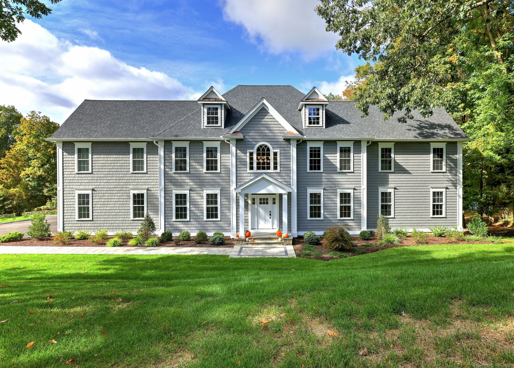 a front view of a house with garden and trees