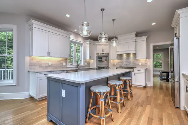 an open kitchen with granite countertop kitchen island wooden floor center island and stainless steel appliances