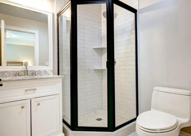 a bathroom with a granite countertop sink toilet and mirror