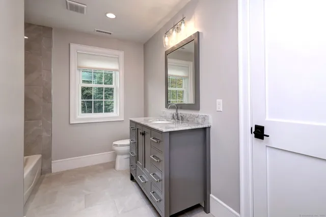 a bathroom with a toilet a sink and a mirror